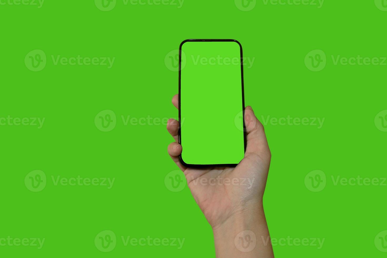 la main d'une femme tient un smartphone avec un écran vert. objet isolé sur fond vert. modèle pour la conception. mocap. photo