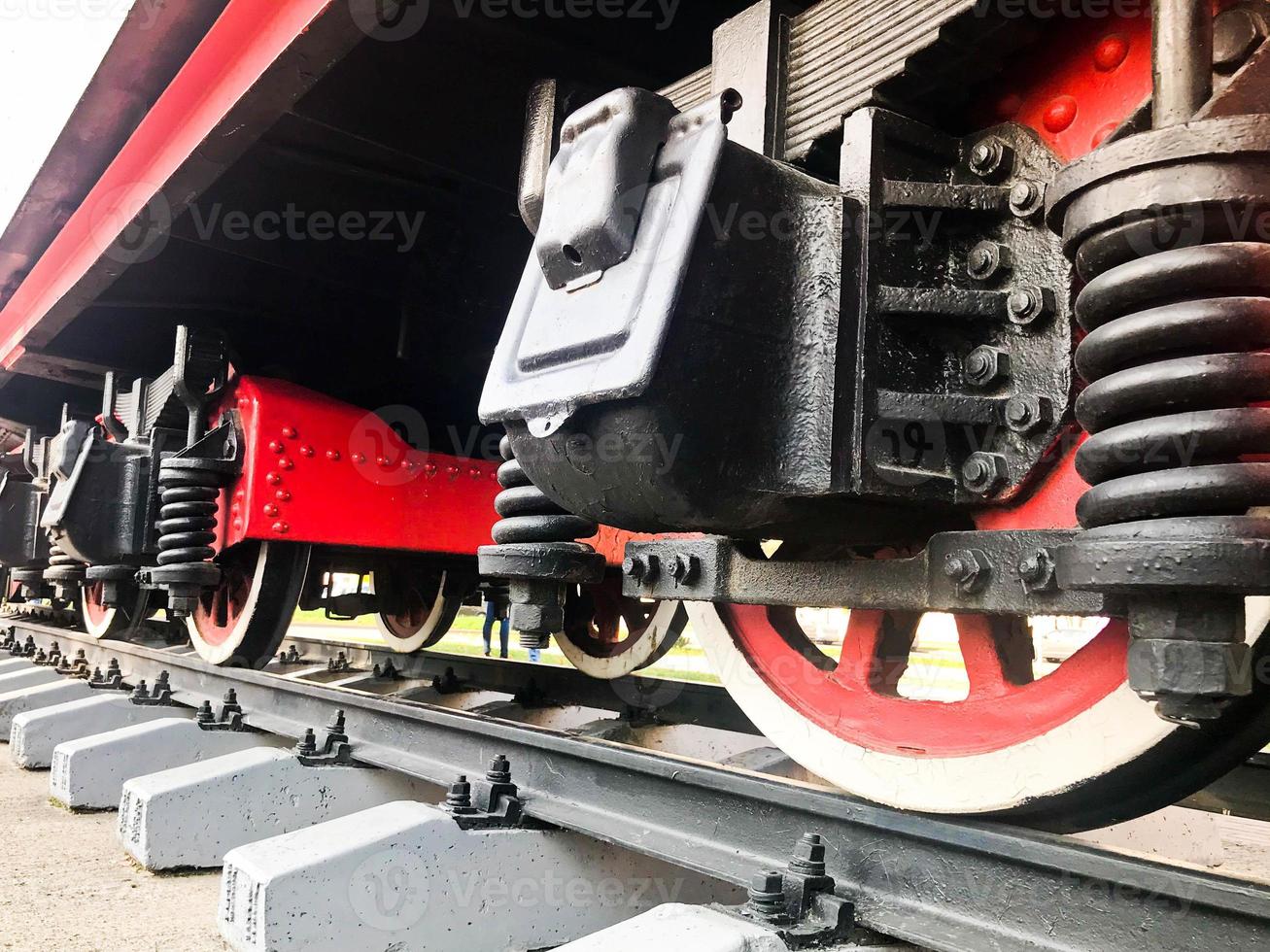 grandes roues en fer d'un train rouge et noir debout sur des rails et éléments de suspension avec ressorts d'une ancienne locomotive à vapeur industrielle photo