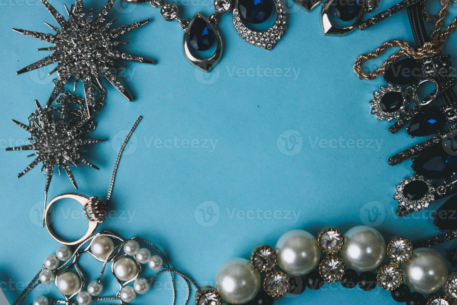 beaux bijoux brillants précieux ensemble de bijoux glamour tendance, collier, boucles d'oreilles, bagues, chaînes, broches avec perles et diamants sur fond bleu. mise à plat, vue de dessus, lieu de copie photo