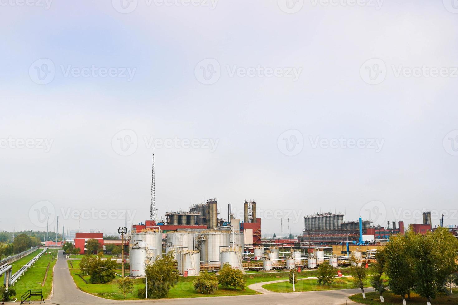 paysage industriel, vue panoramique sur la production. usines chimiques, colonnes, générateurs, tuyaux. systèmes de traitement d'huile. bâtiments de production. sur fond de ciel nuageux et d'arbres photo