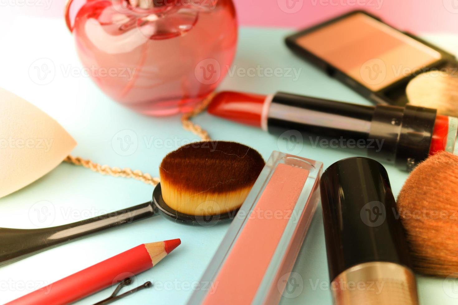 ensemble de cosmétiques féminins de rouge à lèvres, surligneur, crayon à lèvres, pinceaux, pinceaux, parfum, poudre, bijoux sur fond bleu. boîte de beauté mise à plat. vue de dessus photo