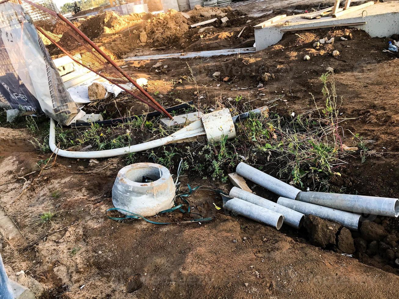 il y a des structures en béton, des pièces de rechange, des tuyaux, des cercles métalliques sur le chantier. pose de communications souterraines. création de drains d'eau pour prévenir la pollution des eaux souterraines photo