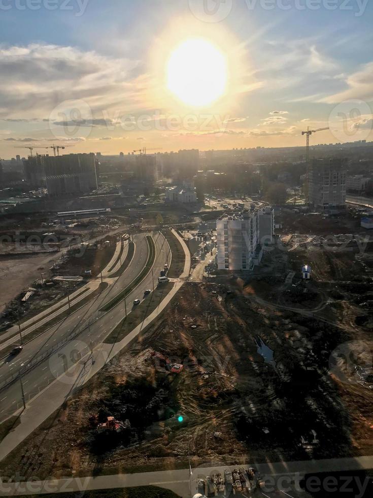 vue ensoleillée sur les nouveaux bâtiments, les bâtiments en construction, les nouvelles maisons. du sable et de la terre creusée pour un quartier branché et moderne. construction dans le centre-ville sous un ciel bleu photo