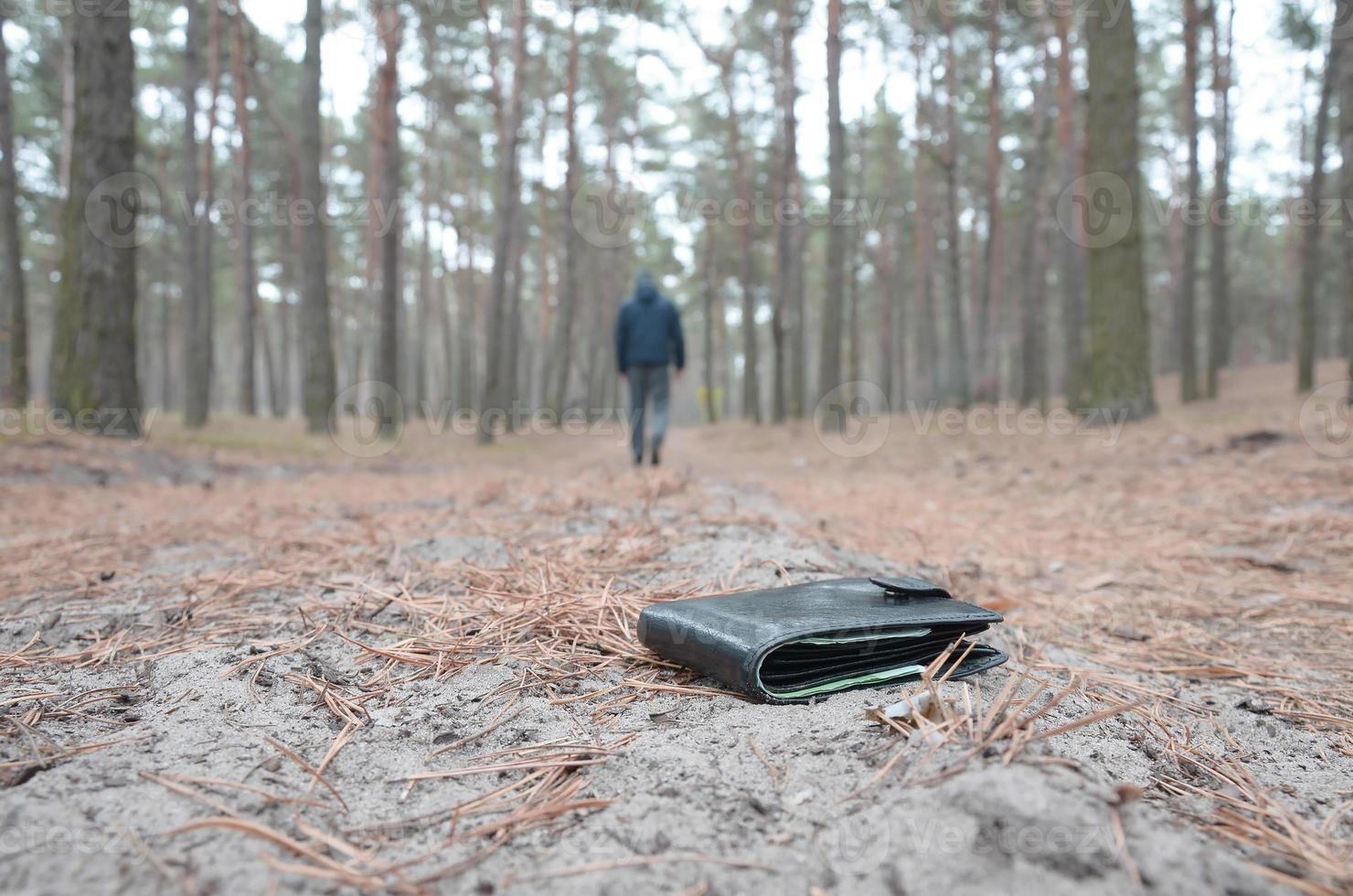 jeune homme perd son sac à main avec des billets en euros sur le chemin du bois de sapin d'automne russe. insouciance et perte de concept de portefeuille photo