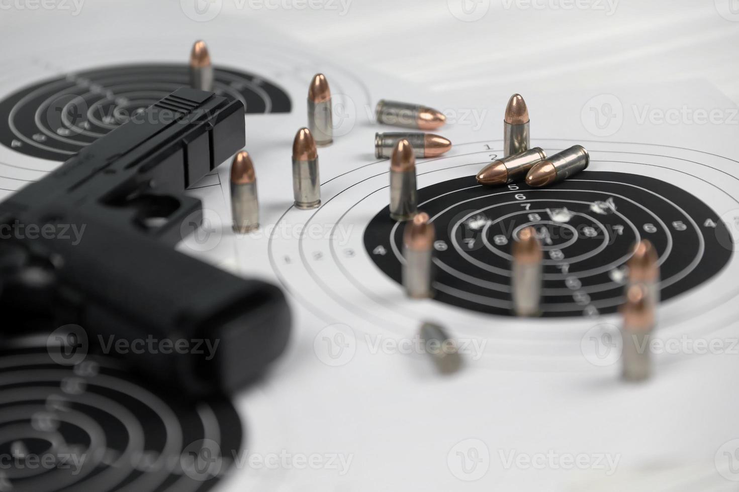 pistolet et de nombreuses balles tirant des cibles sur une table blanche dans un polygone de champ de tir. formation à la visée et au tir photo