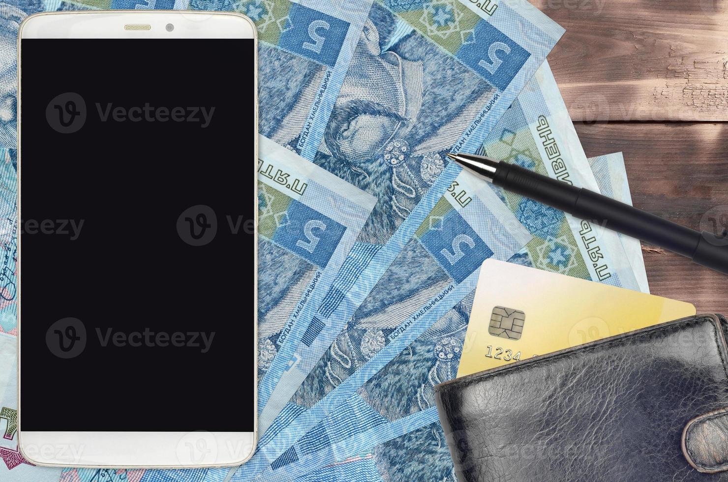 5 factures de hryvnias ukrainiennes et smartphone avec sac à main et carte de crédit. paiements électroniques ou concept de commerce électronique. achats en ligne et affaires avec des appareils portables photo