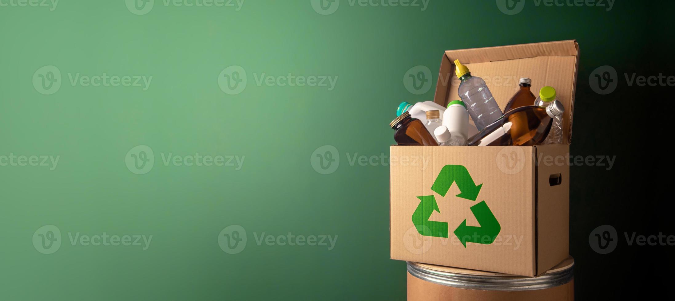 concept de conservation du climat et de l'environnement. recyclage de la boîte en carton ondulé pleine de bouteilles en plastique et en verre contre le mur vert. zéro déchet, moins de plastique. protection de l'environnement et renouvelable photo