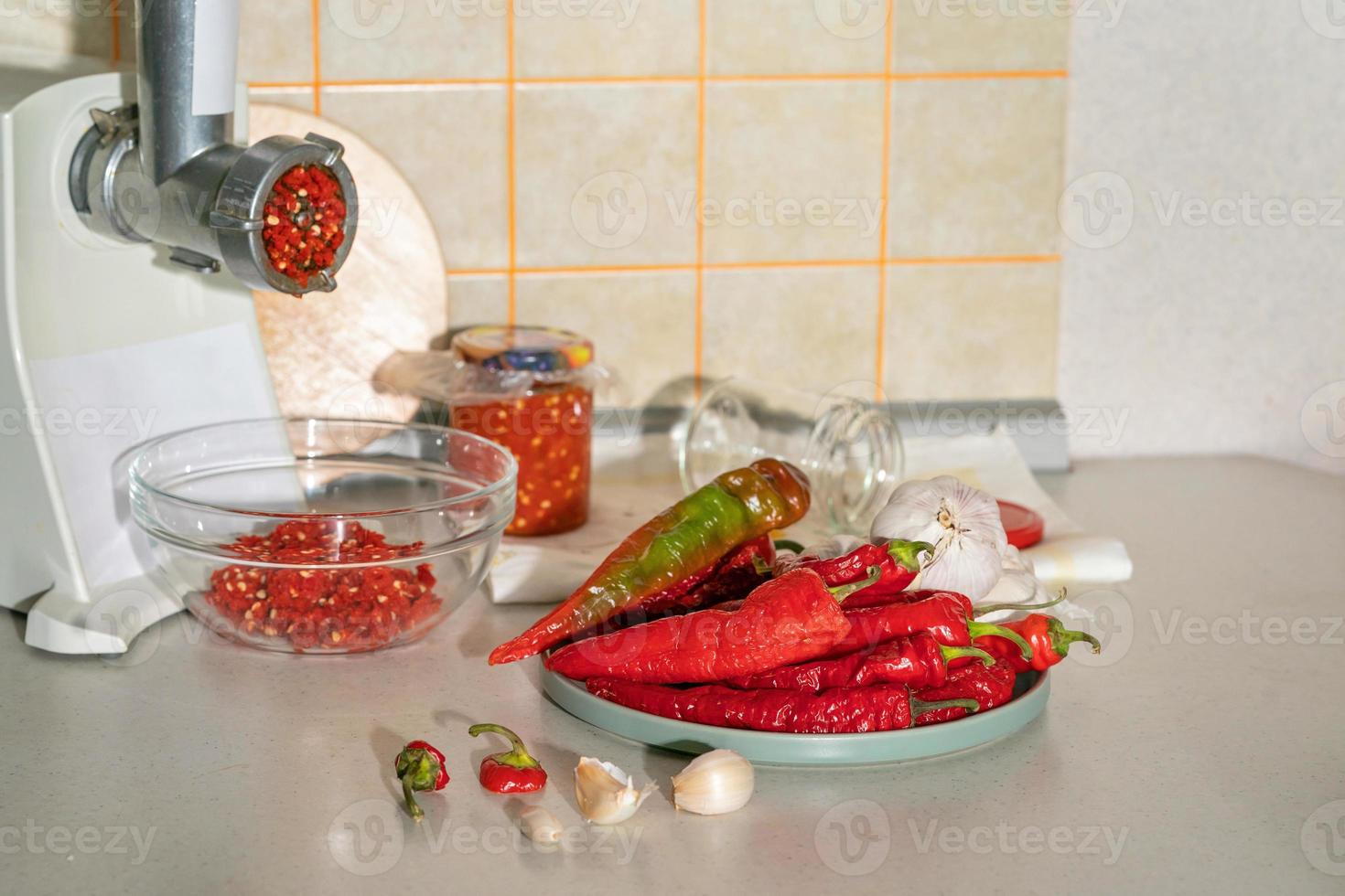 cuisson de l'adjika à partir de piment et d'ail moulus dans un hachoir à viande. préparatifs pour l'hiver. remède populaire contre la grippe et le rhume photo