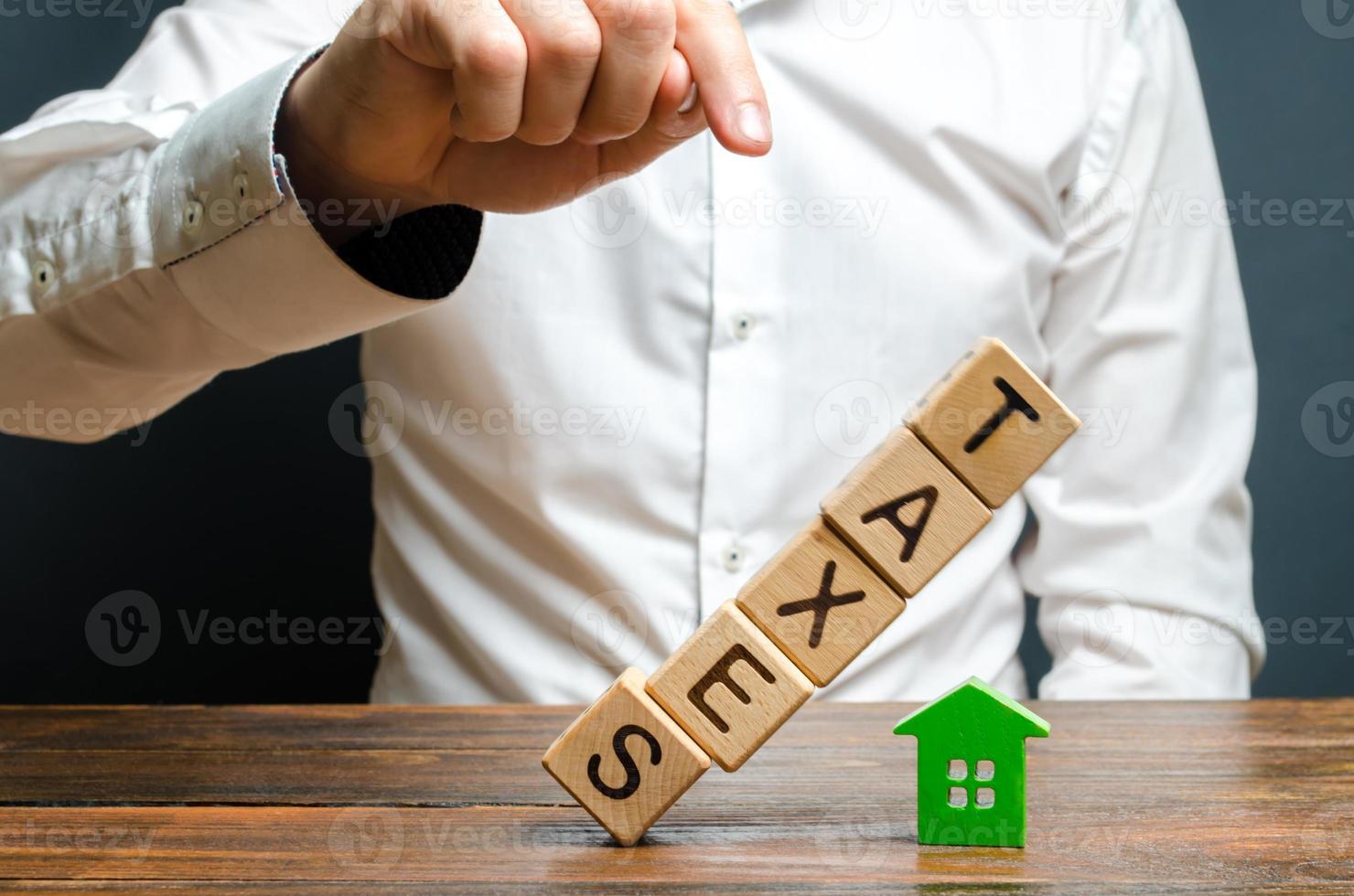 l'homme fait tomber la tour de cubes avec le mot impôts sur la figure de la maison. lourde charge fiscale, manque de liquidité des actifs et de l'immobilier. allégements fiscaux, allègements, lacunes dans les lois. déclaration photo