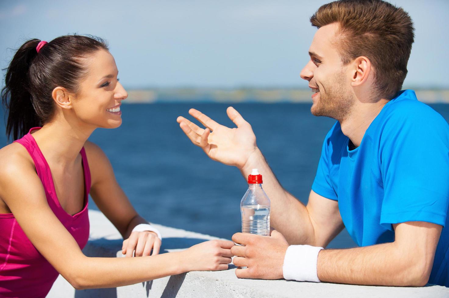 sport reliant les gens. vue latérale d'un beau jeune couple en vêtements de sport debout face à face et parlant photo