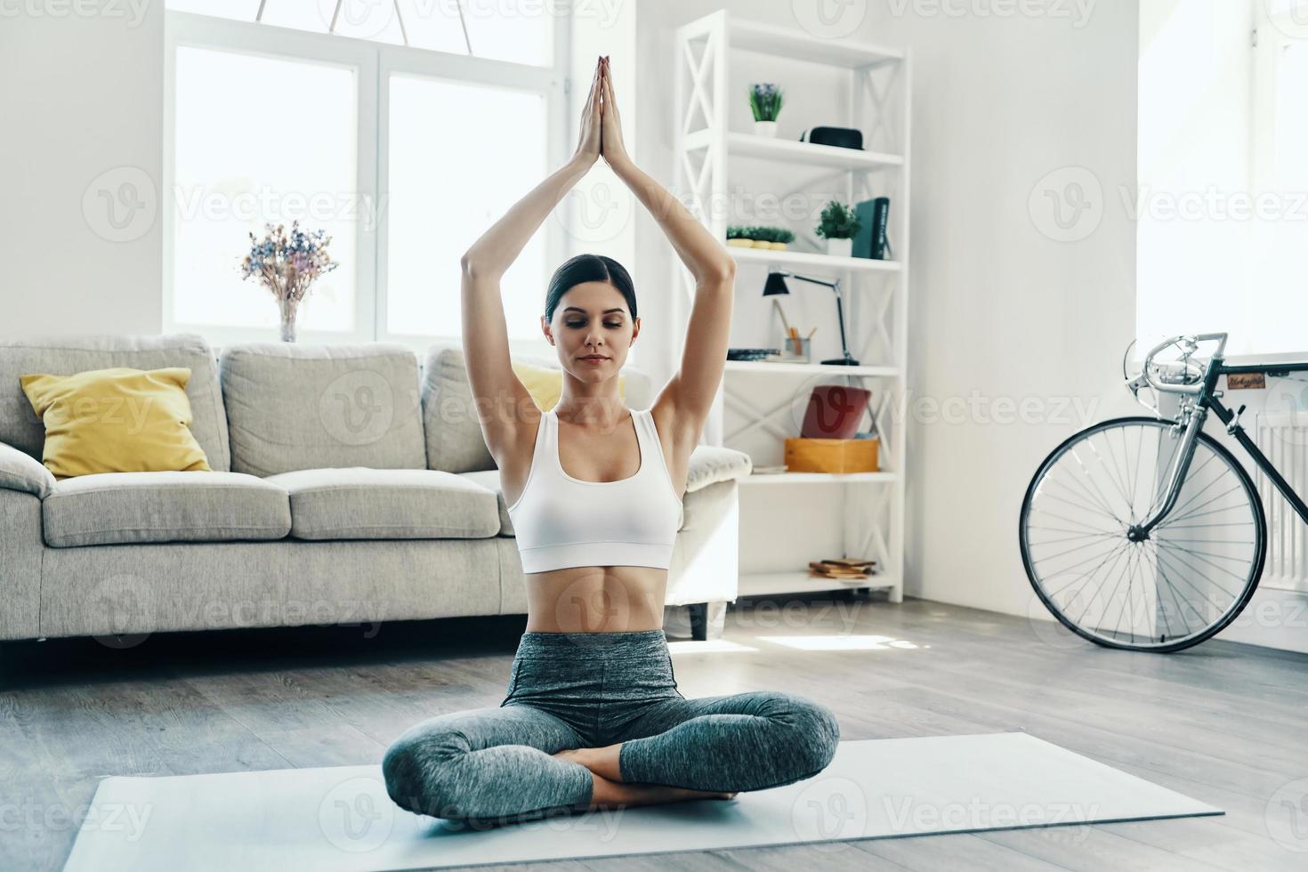 équilibrant son esprit et son corps. belle jeune femme en vêtements de sport pratiquant le yoga tout en passant du temps à la maison photo