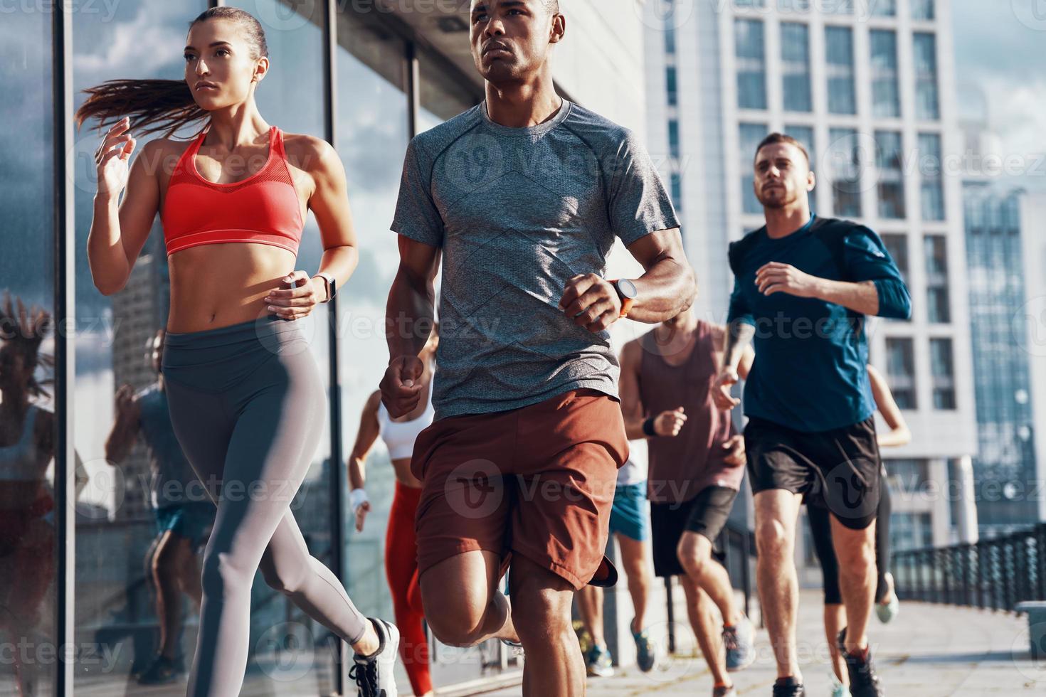 groupe de personnes en vêtements de sport faisant du jogging tout en faisant de l'exercice sur le trottoir à l'extérieur photo