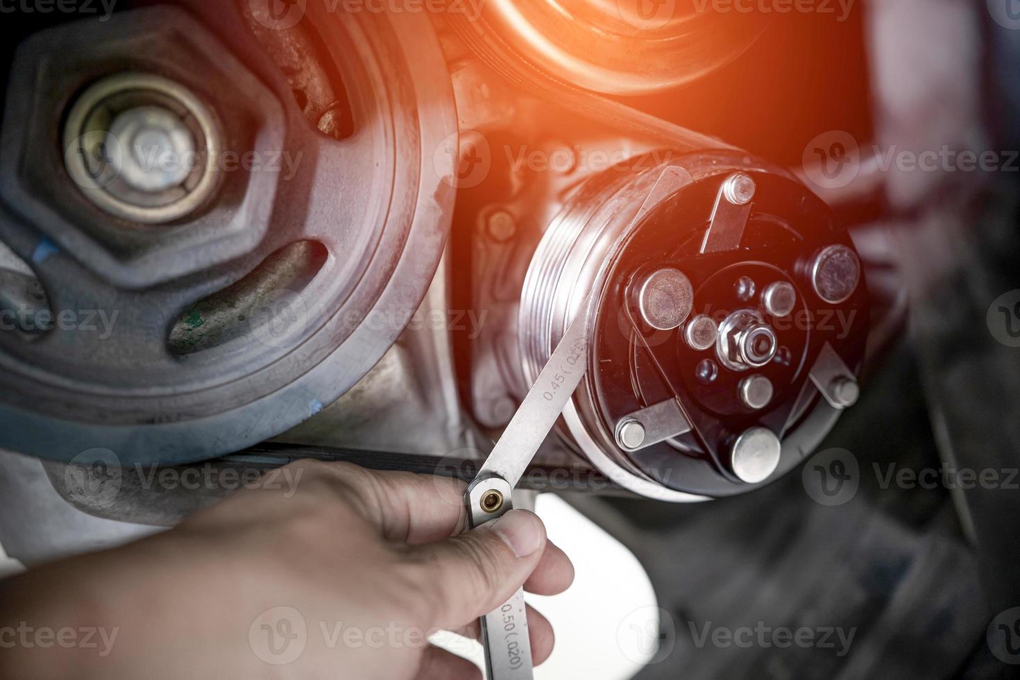 le technicien utilise les portes de remplissage vérifie l'embrayage du compresseur sur le moteur de la voiture dans les travaux de service du climatiseur de la voiture photo