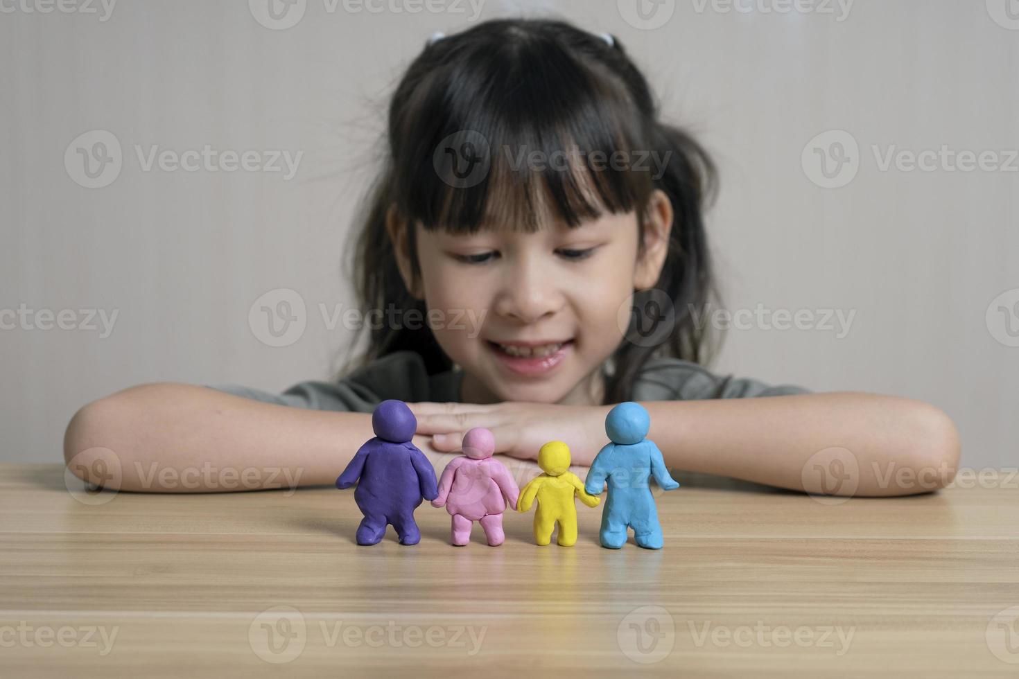 jolie fille asiatique construit une figurine en pâte à modeler de maman, papa et enfant et frère. concept de maison familiale et relations familiales. la chaleur et l'amour de la famille. la créativité et l'apprentissage des enfants photo