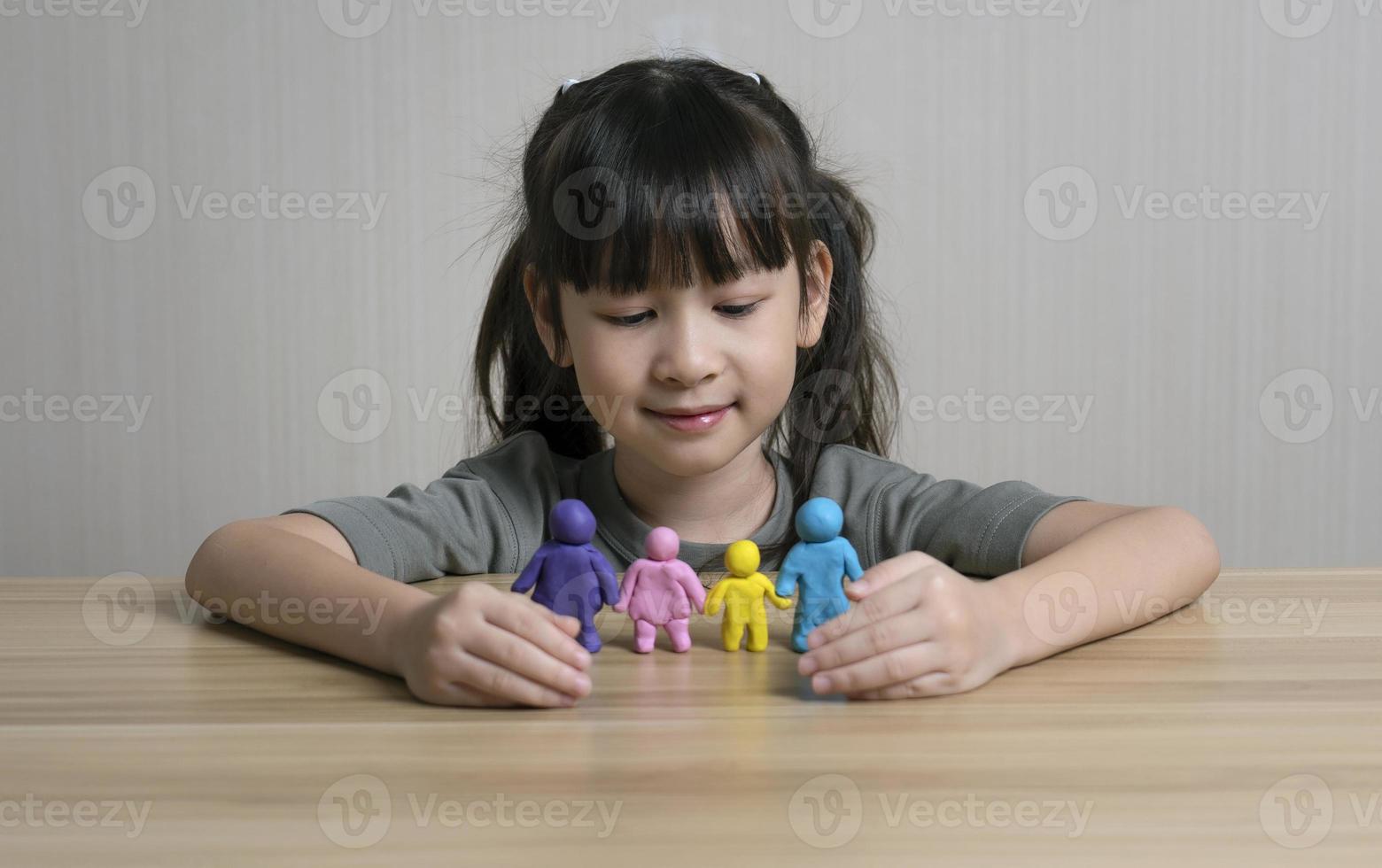 jolie fille asiatique construit une figurine en pâte à modeler de maman, papa et enfant et frère. concept de maison familiale et relations familiales. la chaleur et l'amour de la famille. la créativité et l'apprentissage des enfants photo