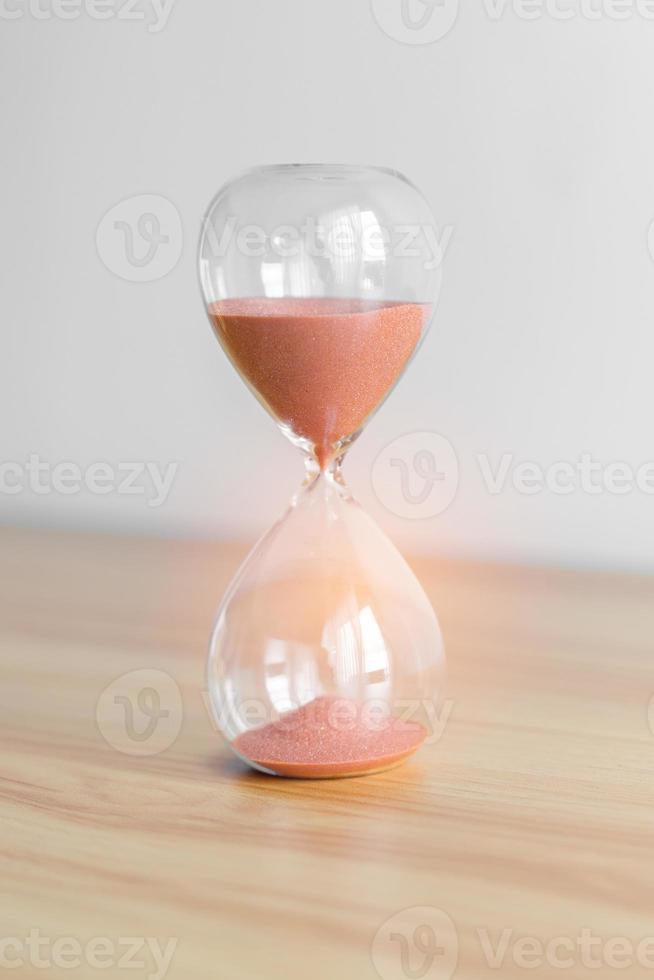 sablier sur table, sable coulant à travers l'ampoule de sablier mesurant le temps qui passe. compte à rebours, patience, date limite, durée de vie et concept de retraite photo