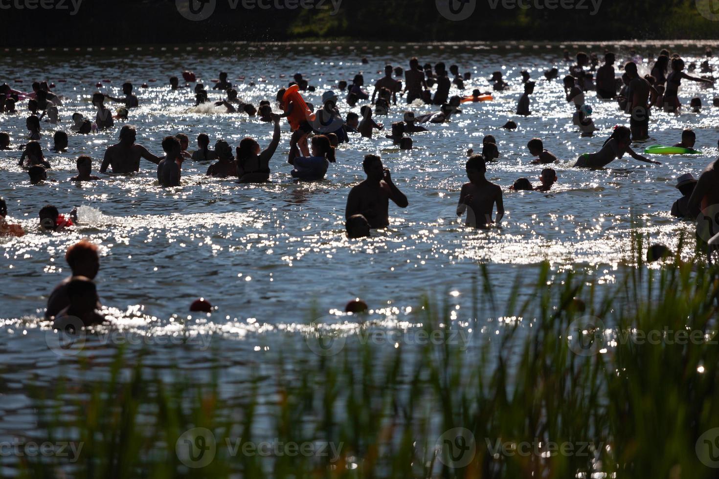 beaucoup de gens se baignent dans l'étang un jour d'été. photo