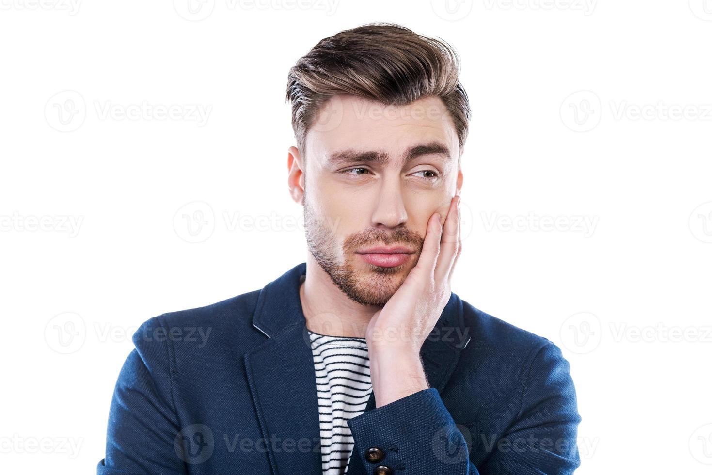 sentiment d'incertitude. portrait d'un jeune homme exprimant son incertitude et regardant ailleurs en se tenant debout sur fond blanc photo