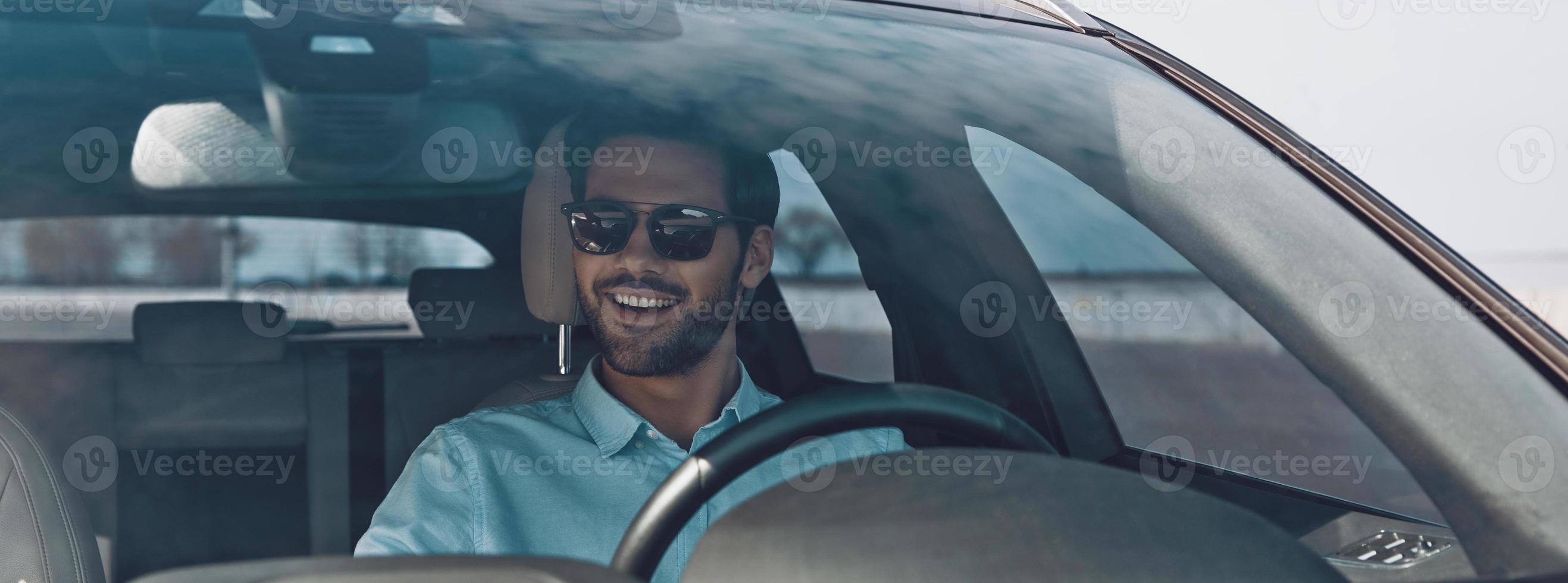 moyen pratique de voyager. beau jeune homme souriant en conduisant une voiture de statut photo