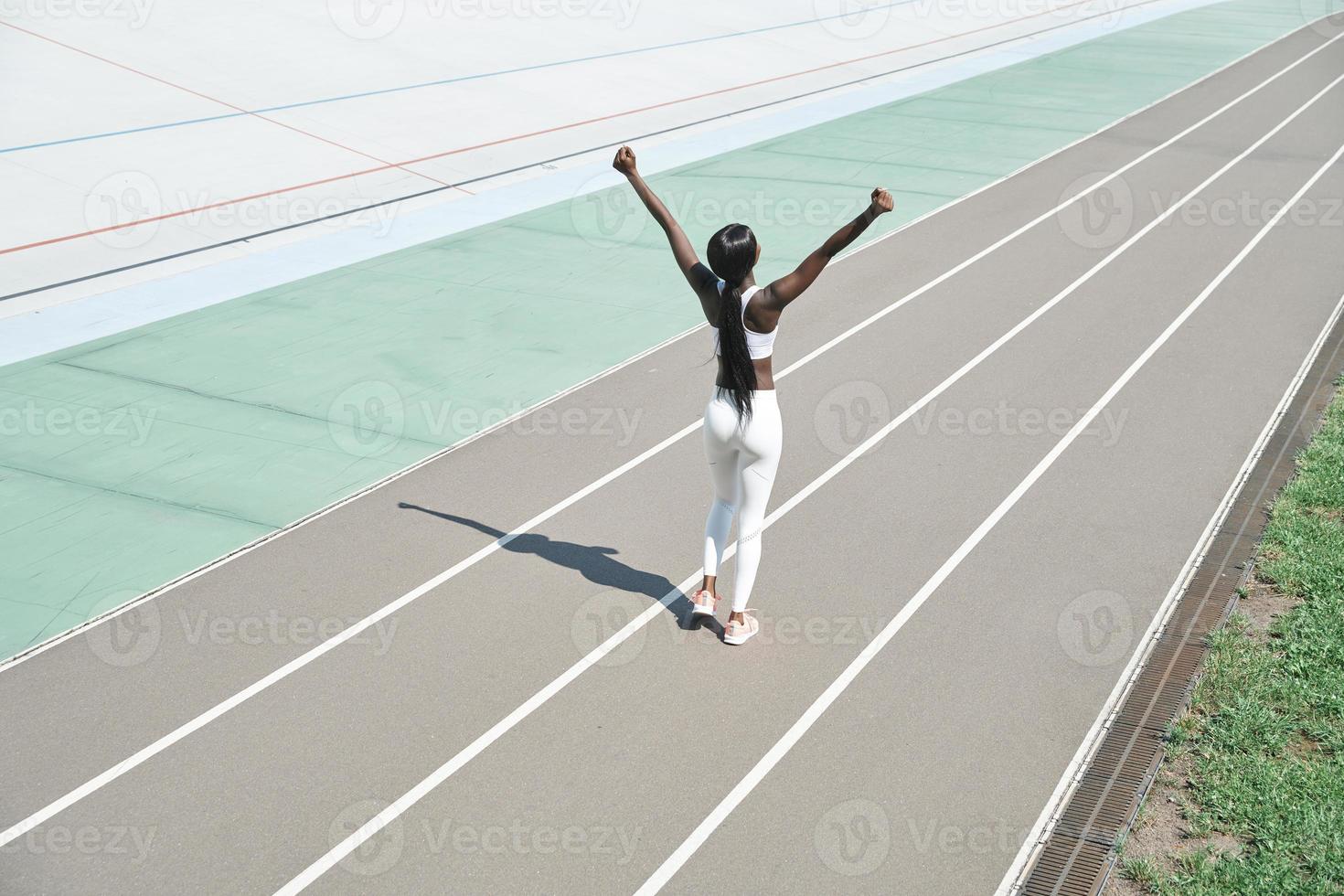 vue de dessus de la belle jeune femme africaine en vêtements de sport en gardant les bras levés photo