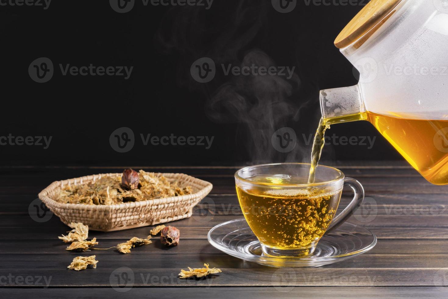 thé de chrysanthème et fleurs de chrysanthème dans un panier sur fond de bois. boisson saine pour un verre. herbes et concepts médicaux. photo