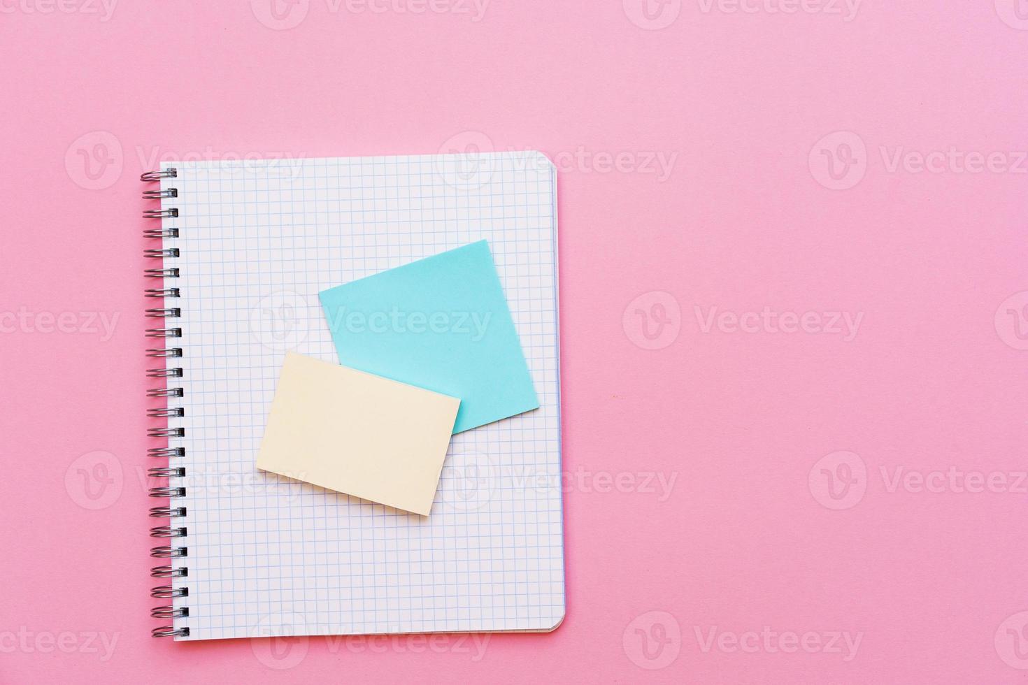 cahier à spirale scolaire sur fond rose des autocollants se trouvent sur le dessus de la feuille. photo