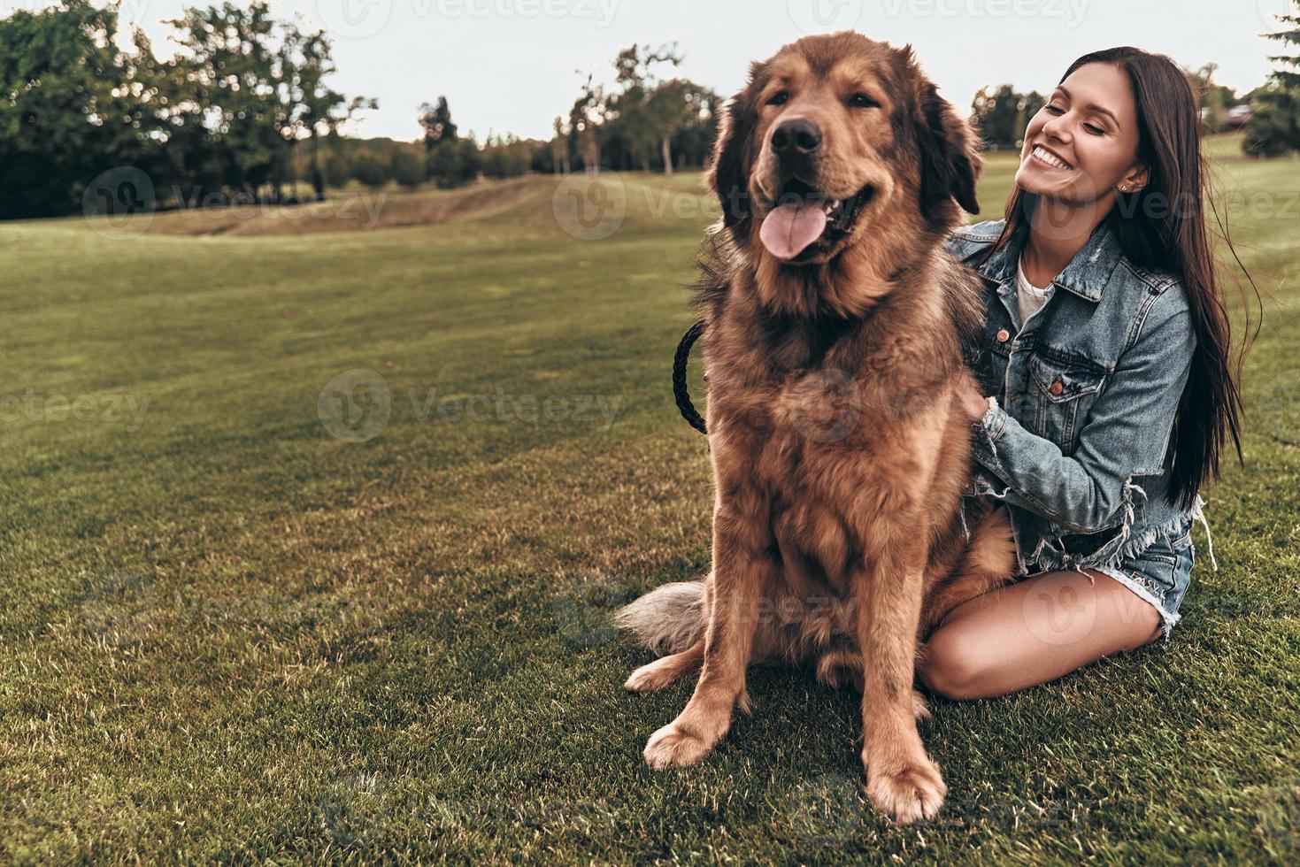 qui est un bon garçon belle jeune femme gardant les yeux fermés et souriant tout en jouant avec son chien à l'extérieur photo