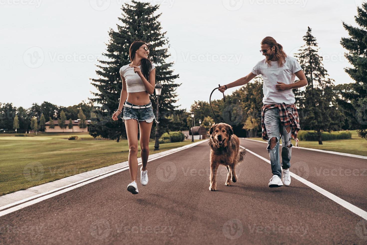 dans un sens. toute la longueur d'un beau jeune couple courant avec son chien tout en passant du temps à l'extérieur photo