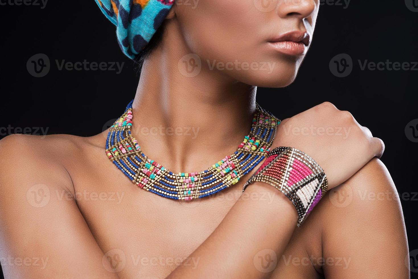 bijoux élégants. photo recadrée d'une belle femme africaine portant un foulard et des bijoux en se tenant debout sur fond noir