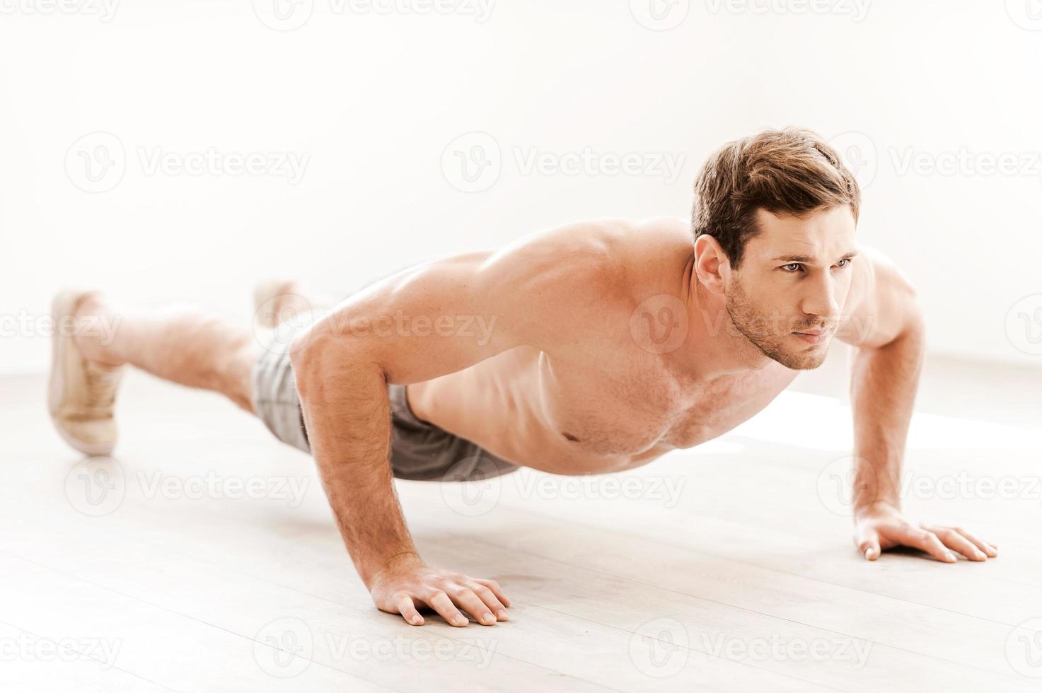 homme faisant des pompes. beau jeune homme musclé faisant des pompes et regardant loin photo