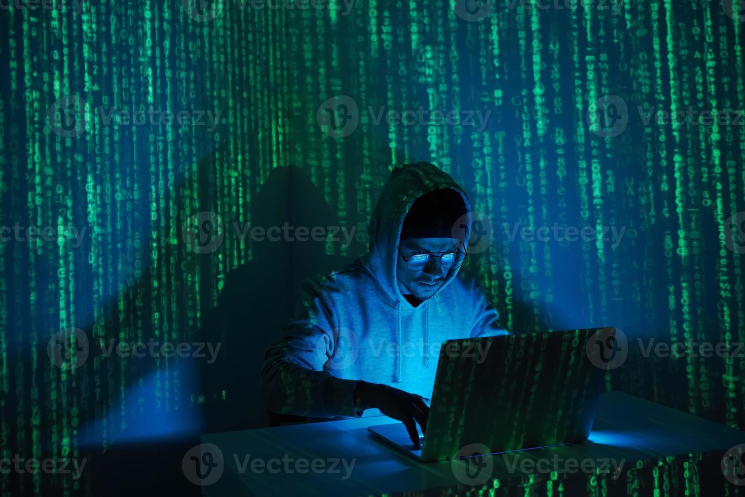 homme concentré en chemise à capuchon à l'aide d'un ordinateur sur un fond sombre photo