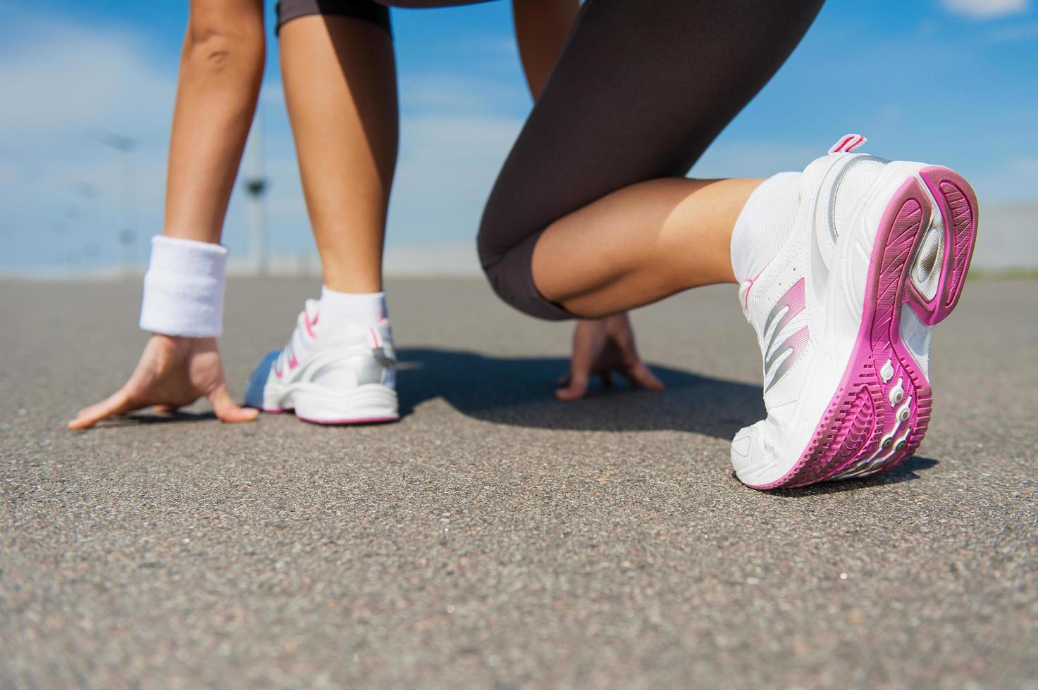 s'apprête à courir. image en gros plan d'une femme en chaussures de sport debout dans la ligne de départ photo
