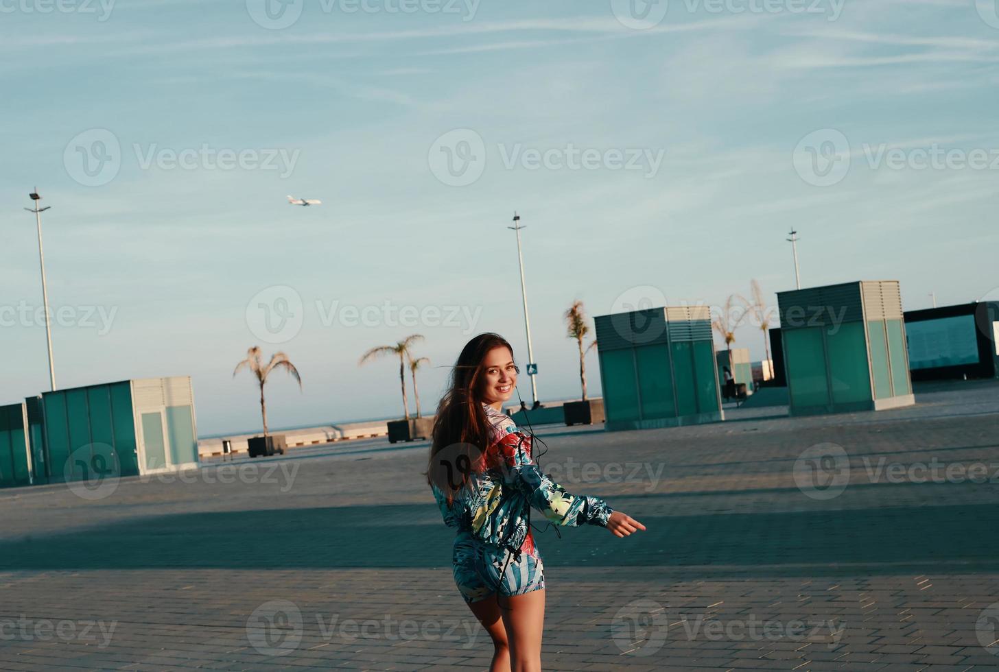 jolie jeune femme en vêtements de sport regardant la caméra et souriant tout en marchant à l'extérieur photo