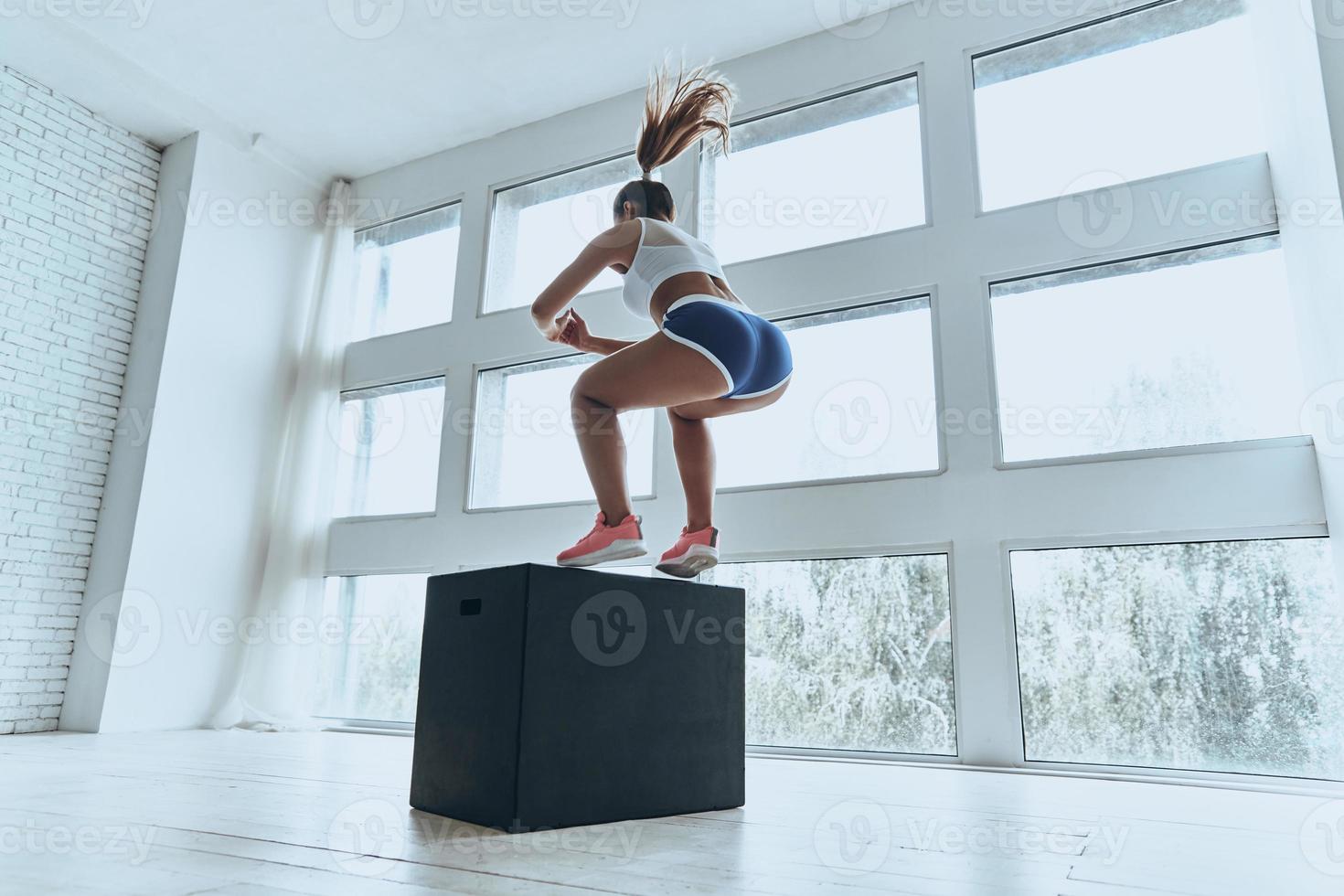 ne jamais abandonner. jeune femme moderne en vêtements de sport sautant pendant l'exercice dans la salle de gym photo