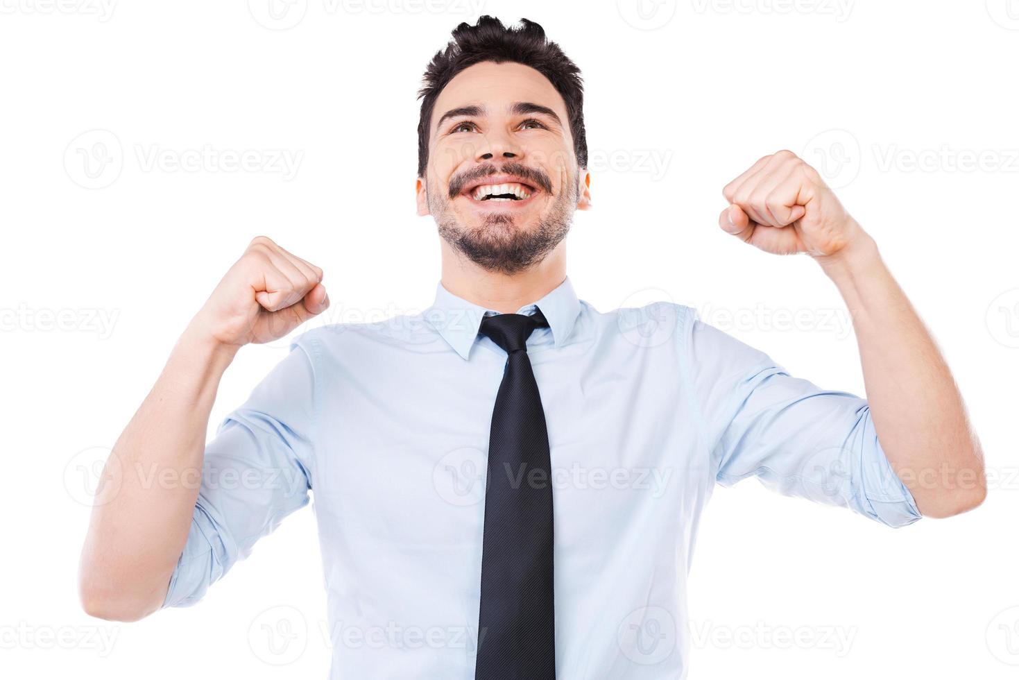 jeune et prospère. heureux jeune homme en chemise et cravate en gardant les bras levés et souriant en se tenant debout sur fond blanc photo