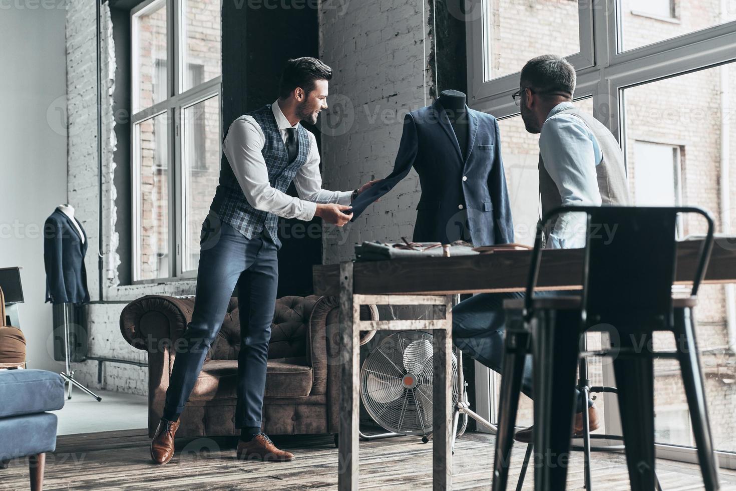 partager des idées. deux jeunes hommes à la mode discutent et sourient en se tenant debout dans un atelier photo