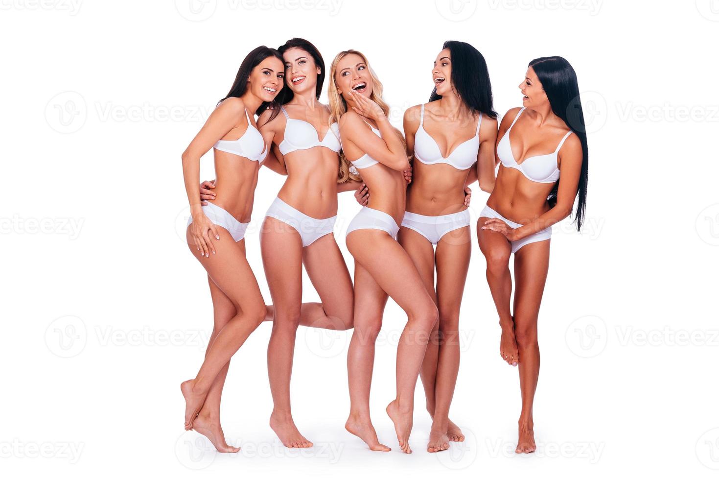 se sentir bien et avoir fière allure. pleine longueur de cinq belles femmes en lingerie posant et semblant naturelles tout en se tenant ensemble sur fond blanc photo