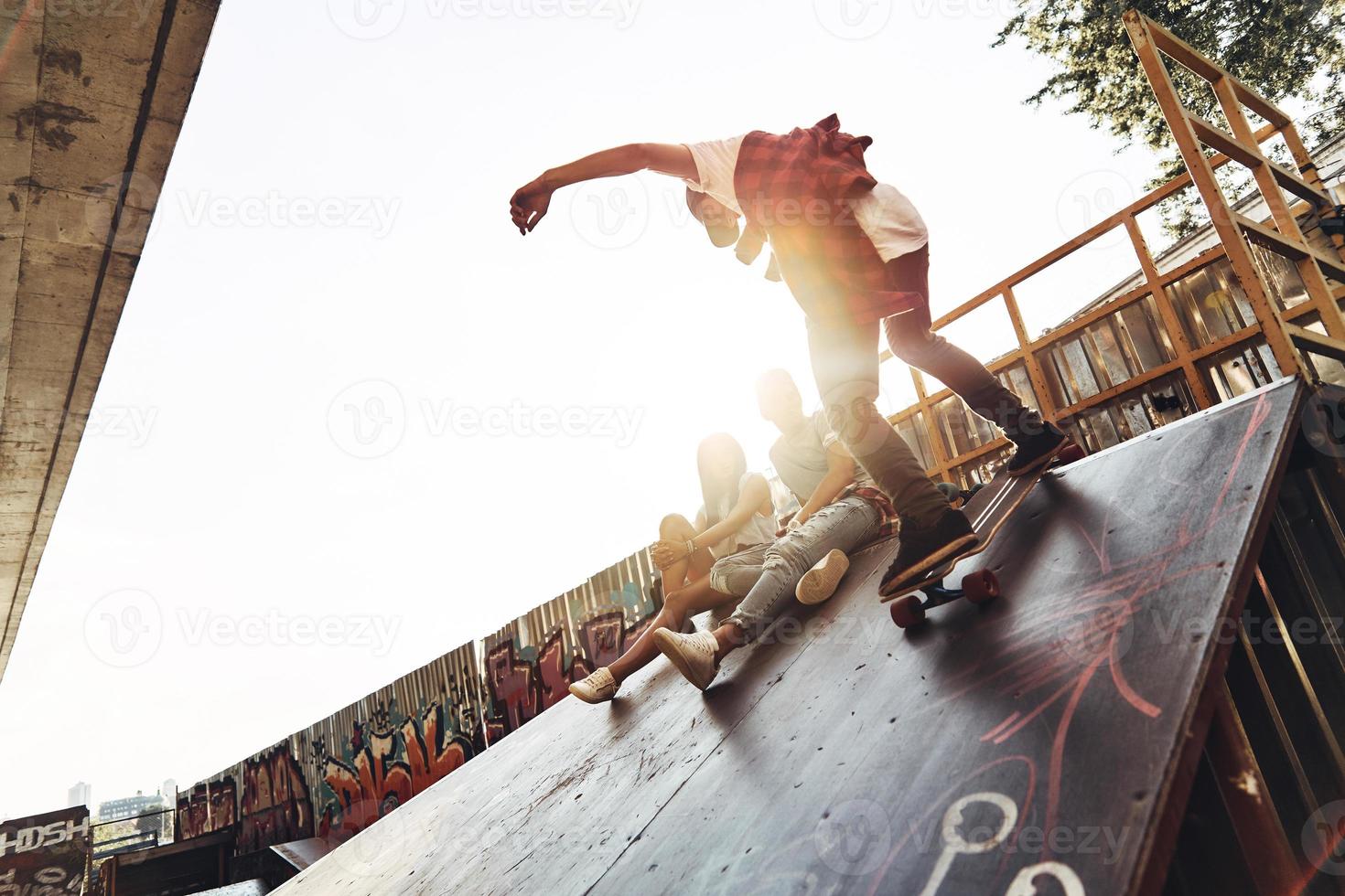 né pour l'embarquement. jeunes hommes modernes faisant du skateboard tout en traînant avec ses amis à l'extérieur photo