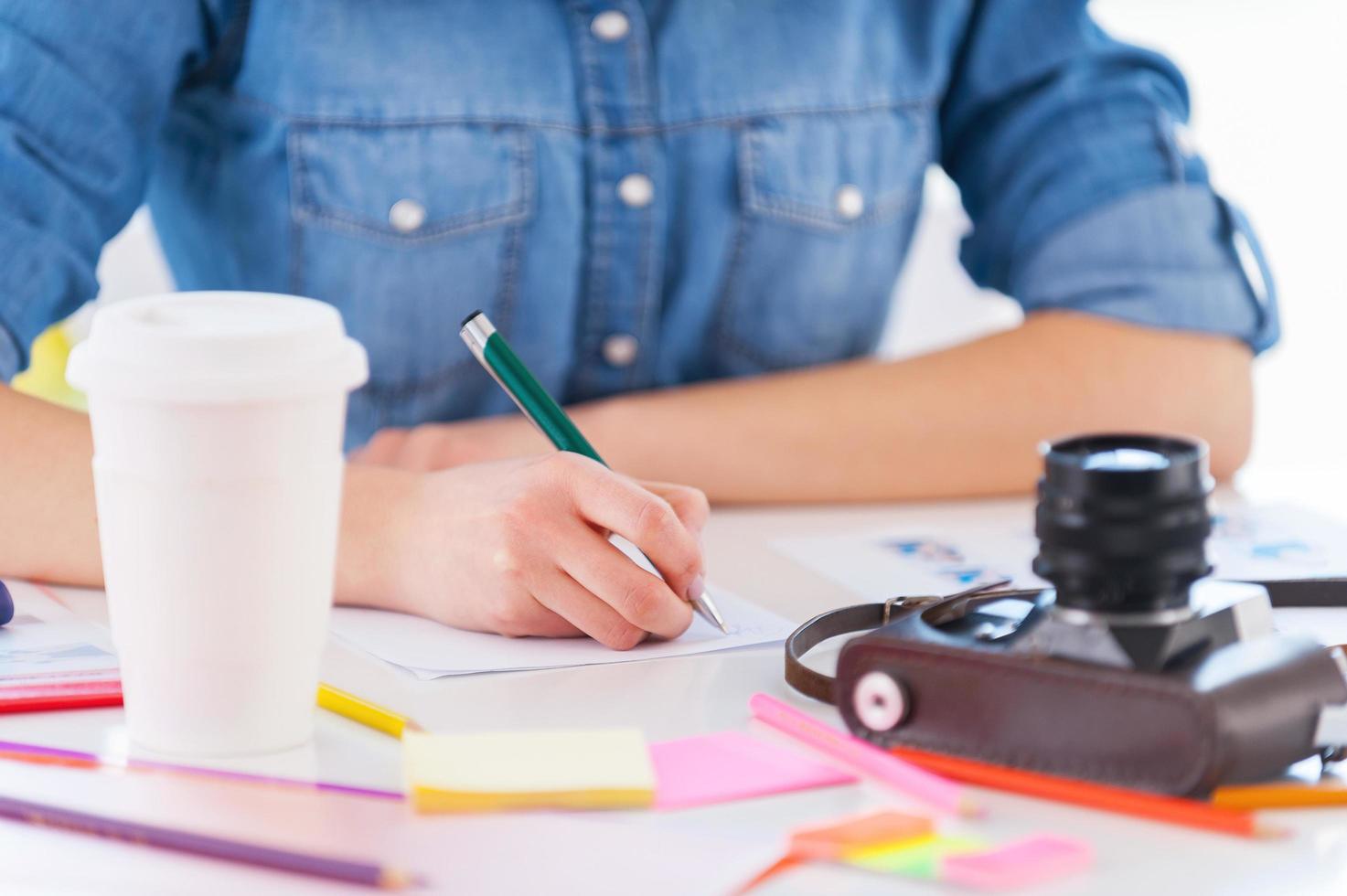 travailler avec plaisir. image recadrée d'une jeune femme d'affaires en tenue décontractée assise sur son lieu de travail et écrivant quelque chose dans son bloc-notes photo