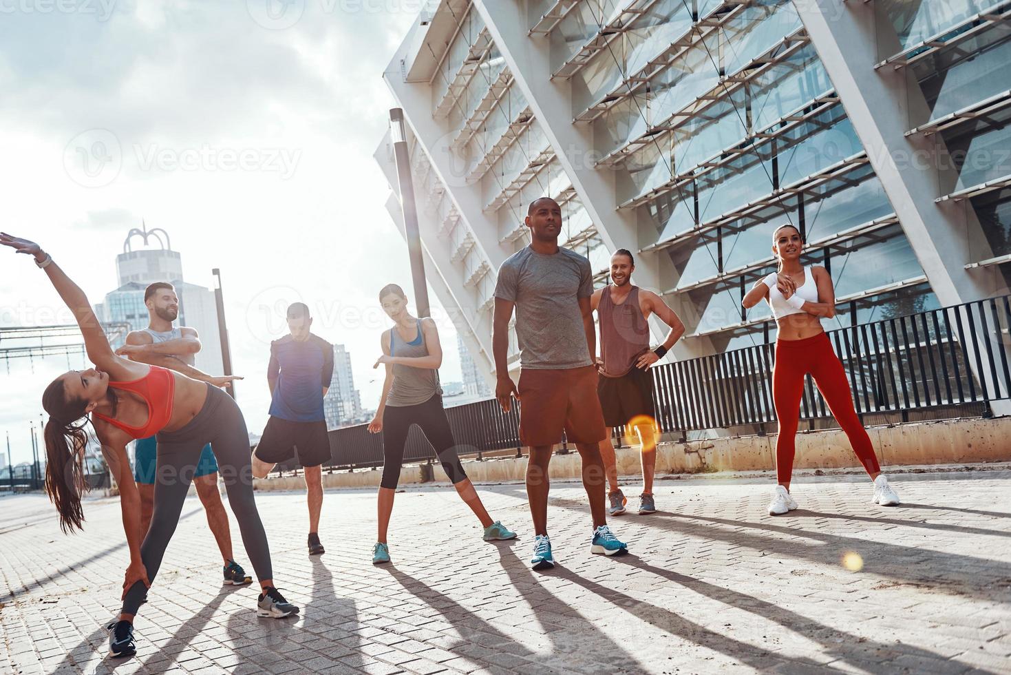 toute la longueur des personnes en vêtements de sport s'échauffant et s'étirant pendant l'exercice à l'extérieur photo