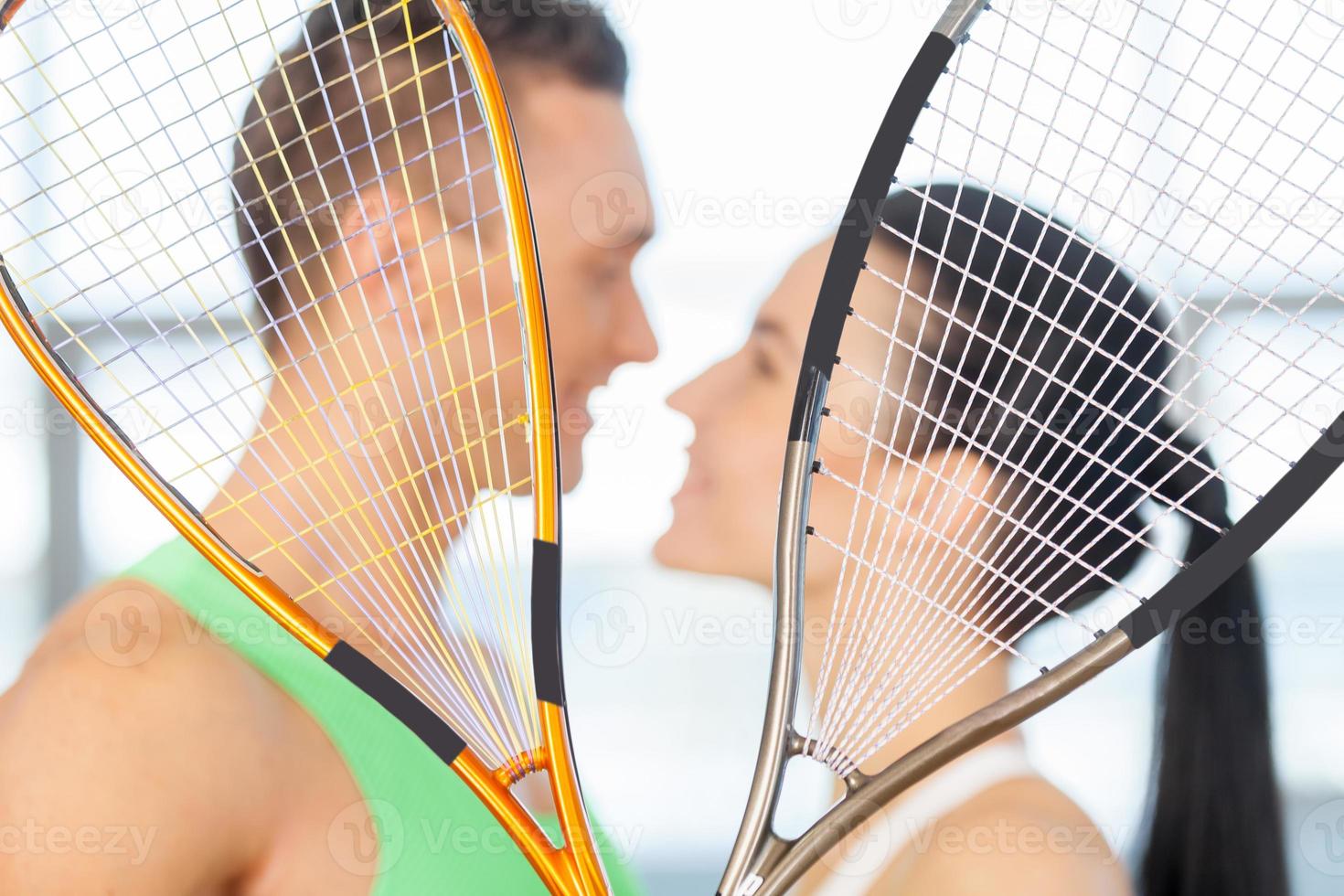 couple de remise en forme. couple d'amoureux s'embrassant derrière une raquette de tennis photo