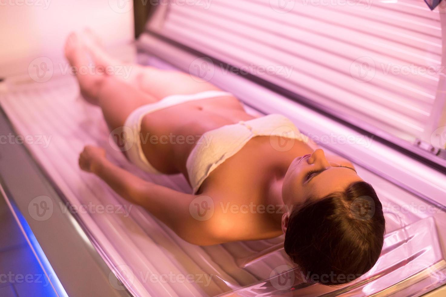 femme sur lit de bronzage. vue de dessus de jolie jeune femme allongée sur un lit de bronzage photo