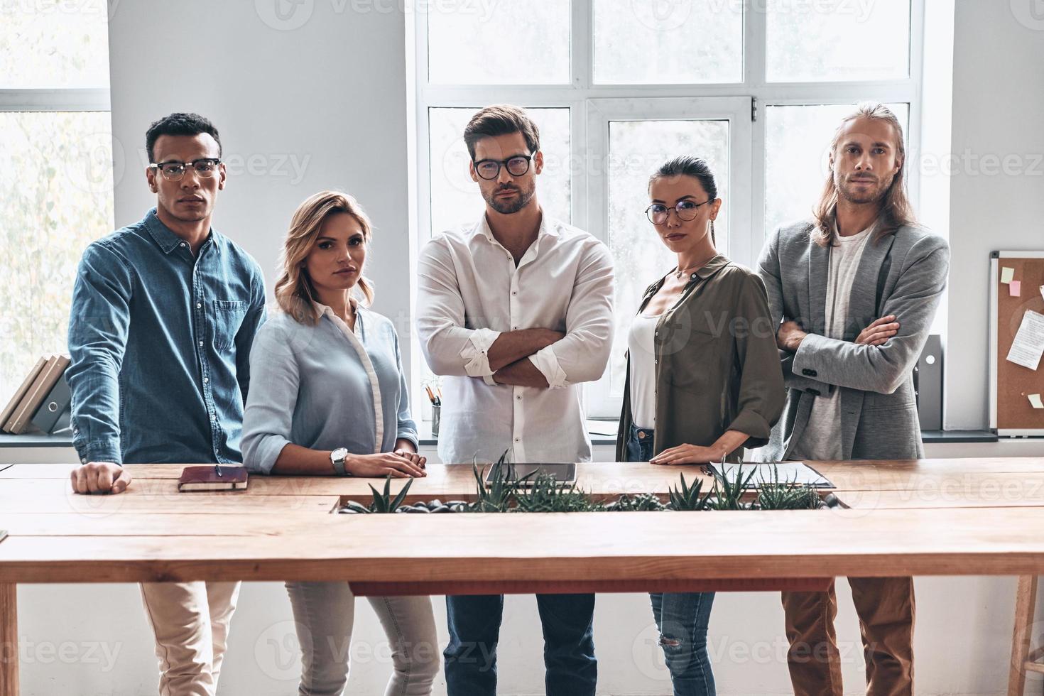 nous sommes le meilleur groupe d'équipe de jeunes gens modernes en vêtements décontractés intelligents regardant la caméra tout en se tenant dans le bureau de création photo