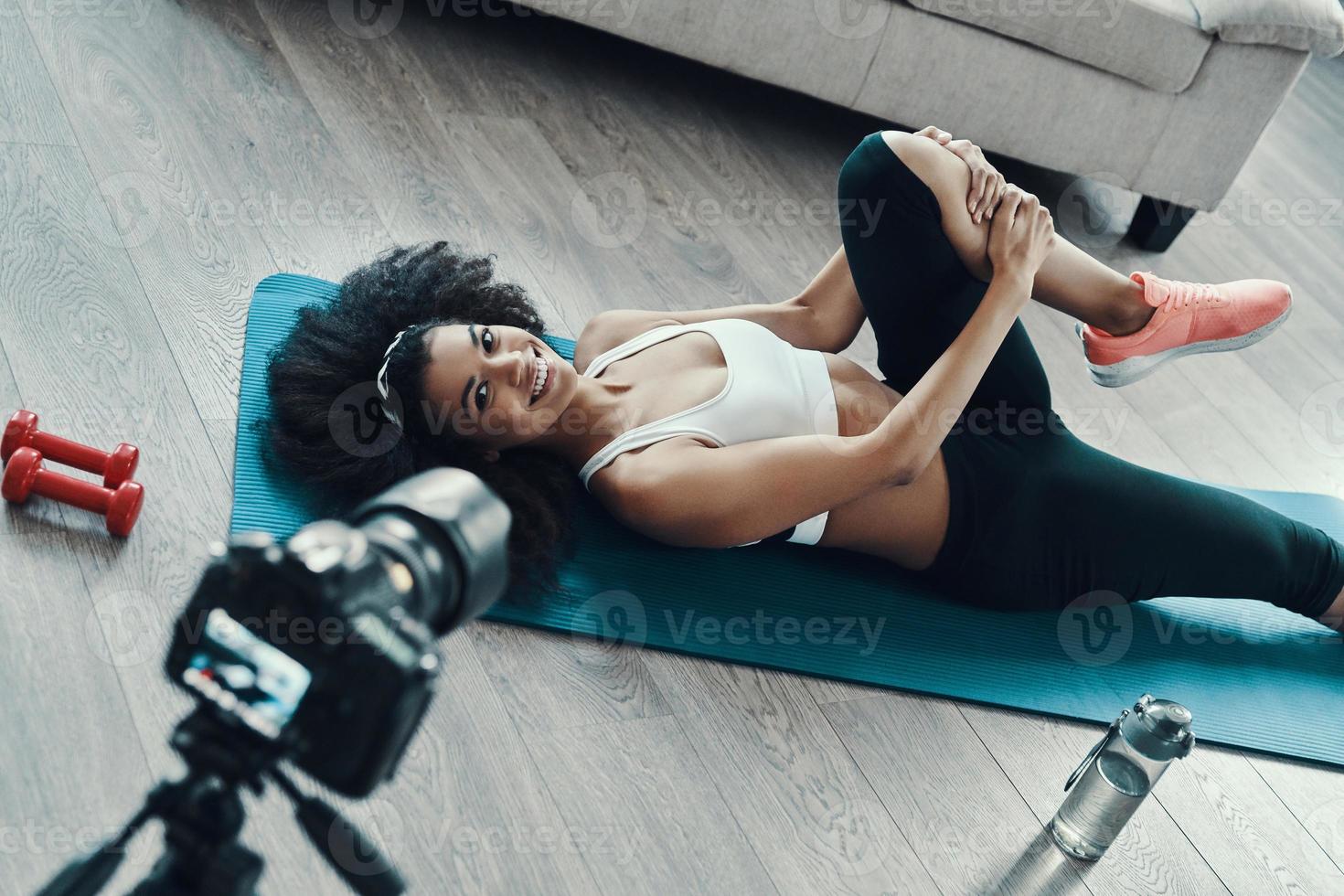 vue de dessus d'une jeune femme africaine en forme travaillant et souriant et montre l'exercice tout en faisant une vidéo sociale photo