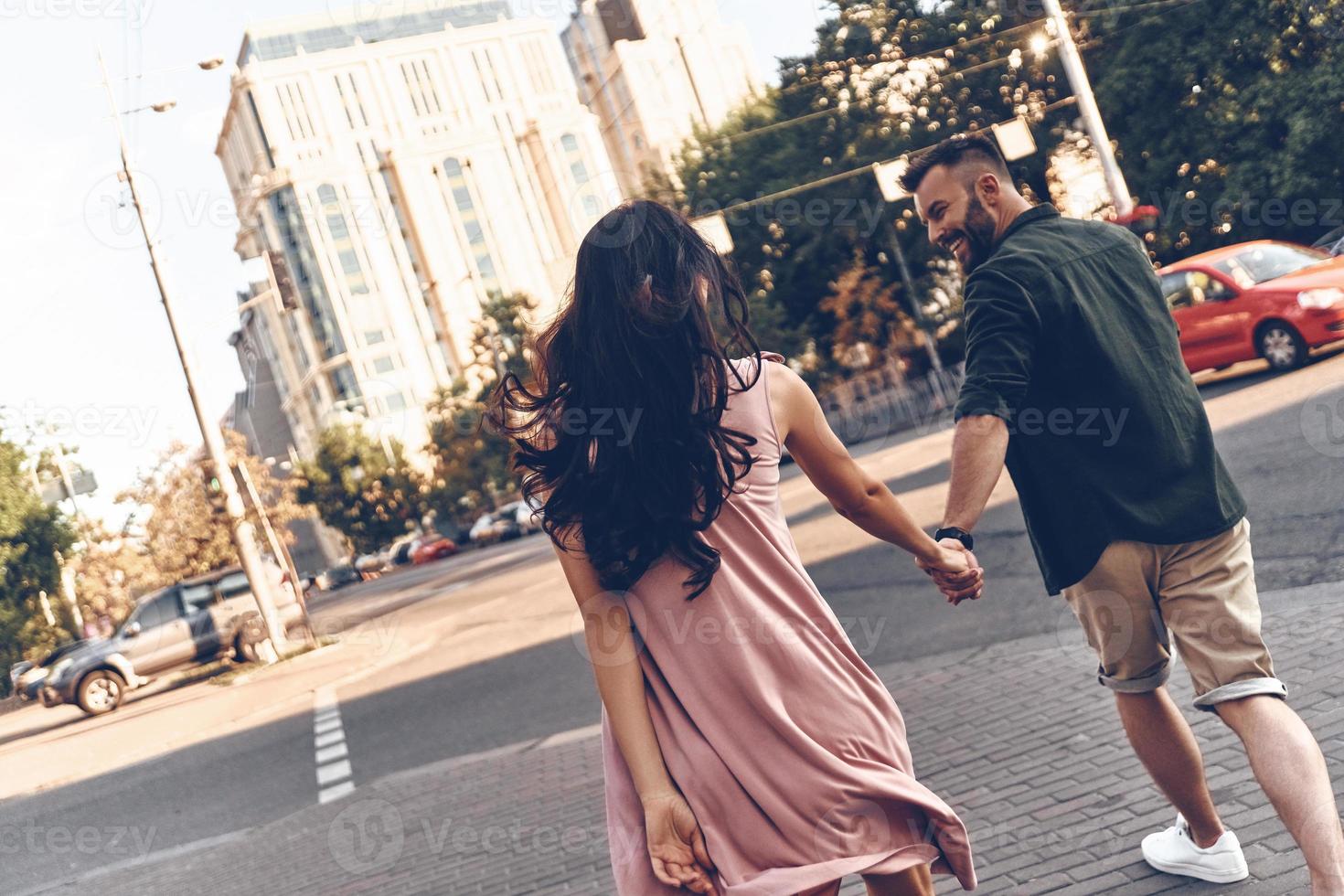 jeune et plein d'énergie. vue arrière du beau jeune couple main dans la main en marchant dans la rue de la ville photo