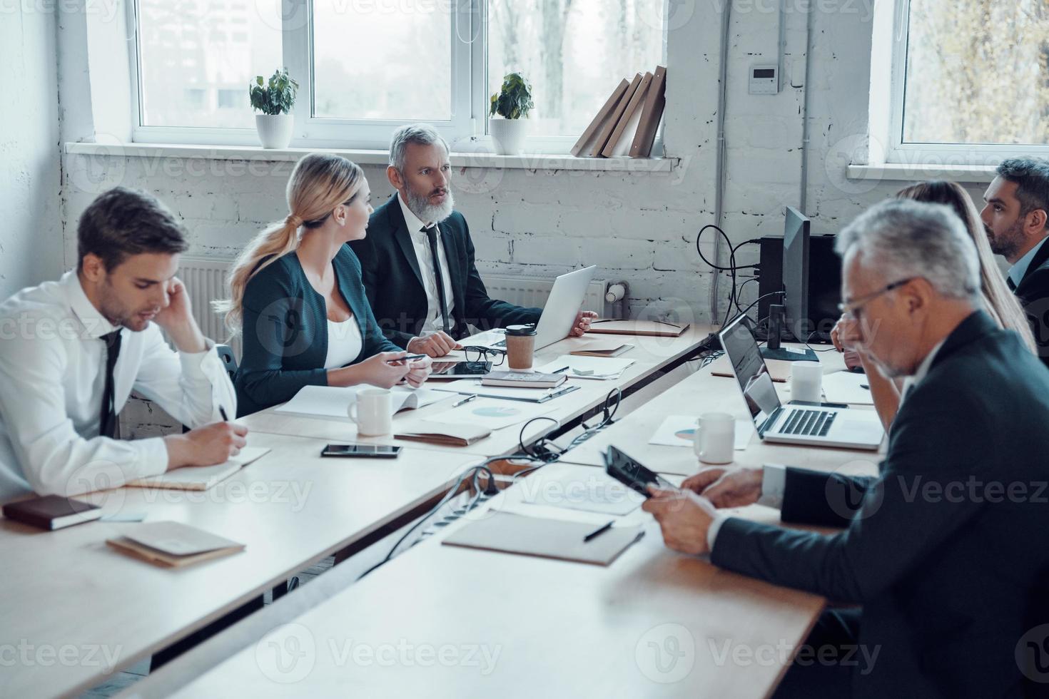 collègues en tenues de soirée élégantes utilisant des technologies modernes tout en travaillant au bureau photo