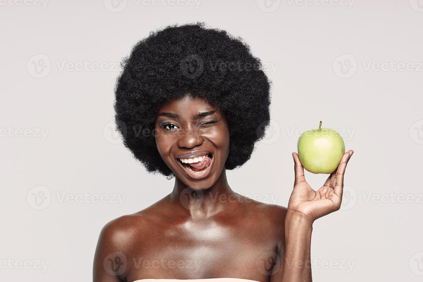 portrait d'une belle jeune femme africaine tenant une pomme verte et un clin d'œil photo