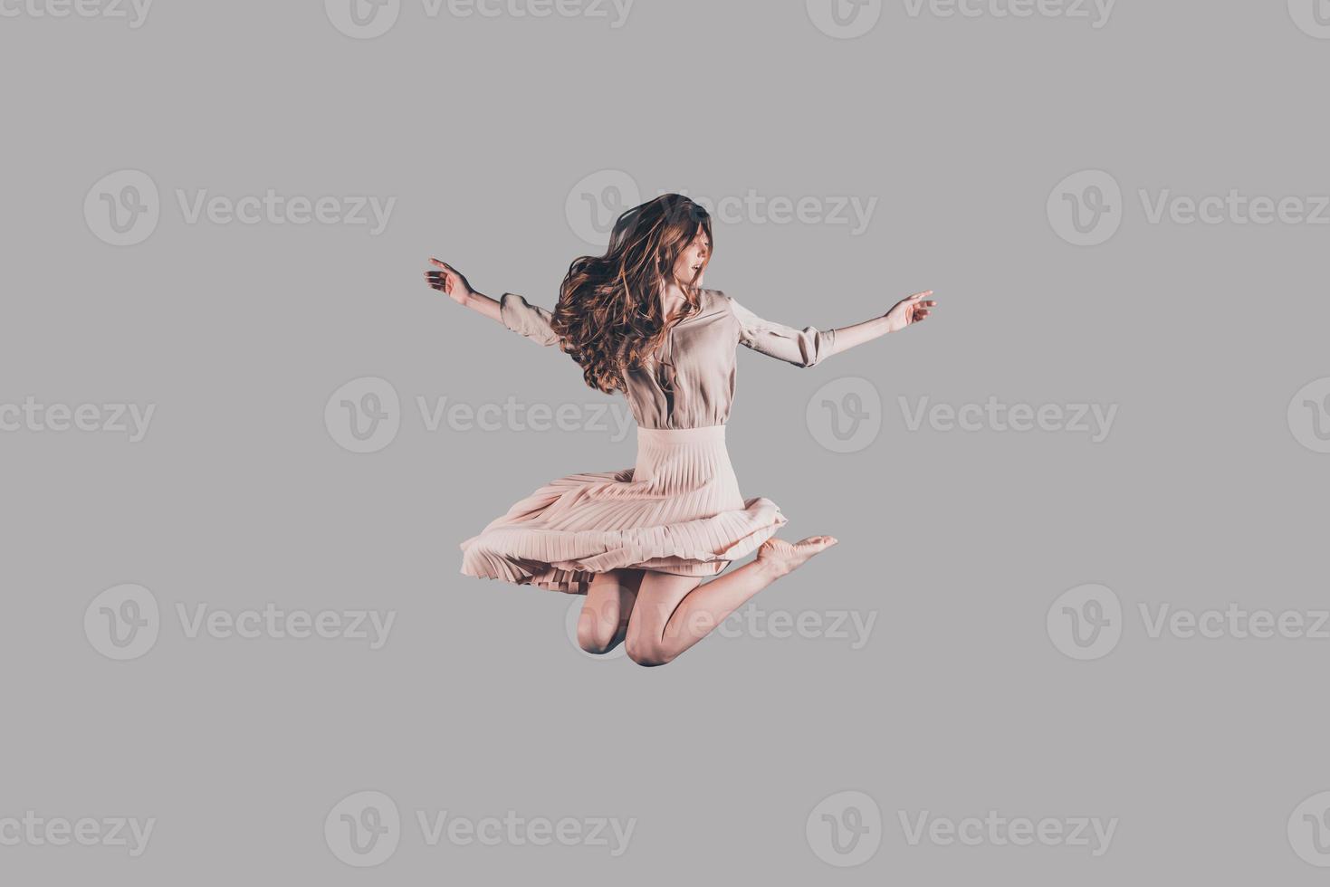 voler comme un oiseau. prise de vue en studio d'une jeune femme attirante planant dans l'air photo