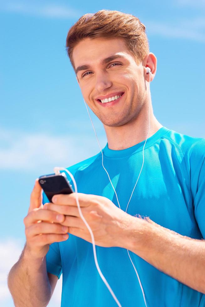 confiant et sportif. beau jeune homme en vêtements de sport debout à l'extérieur et souriant photo