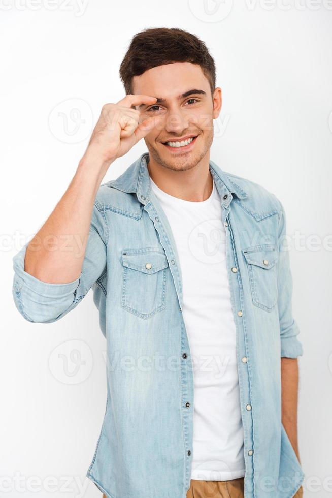 c'était aussi proche que gai jeune homme gesticulant et souriant en se tenant debout sur fond blanc photo